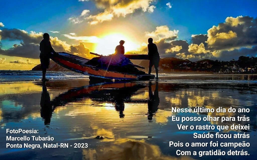 Jangada e silhuetas ao pôr do sol, refletidas na areia molhada, com versos de Marcello Tubarão.
